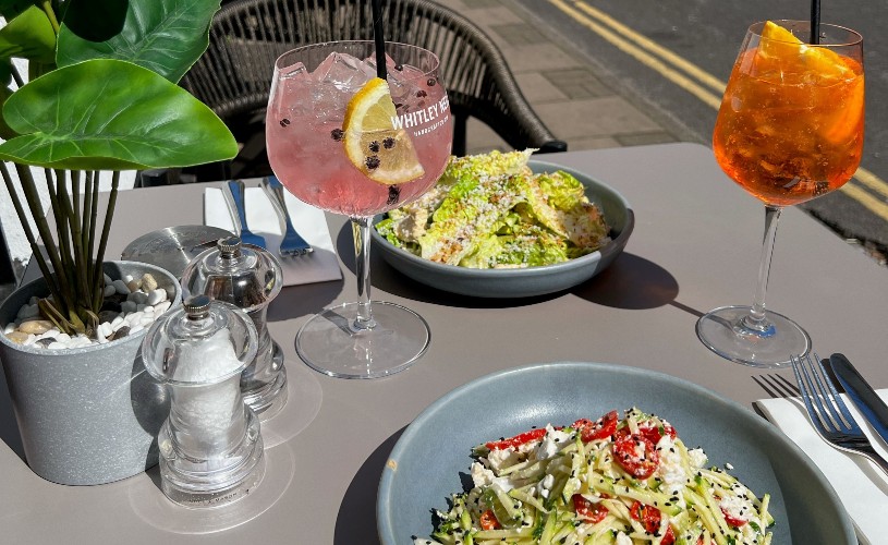 Food and cocktails on outdoor table at Pizza on the Park